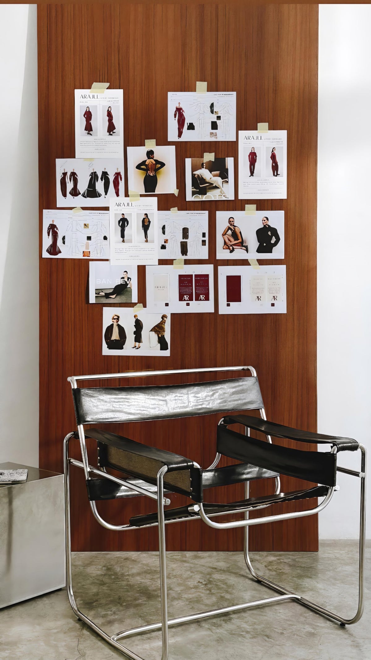 ARAJLL design moodboard pinned to a wooden wall above a black leather and chrome chair in the studio