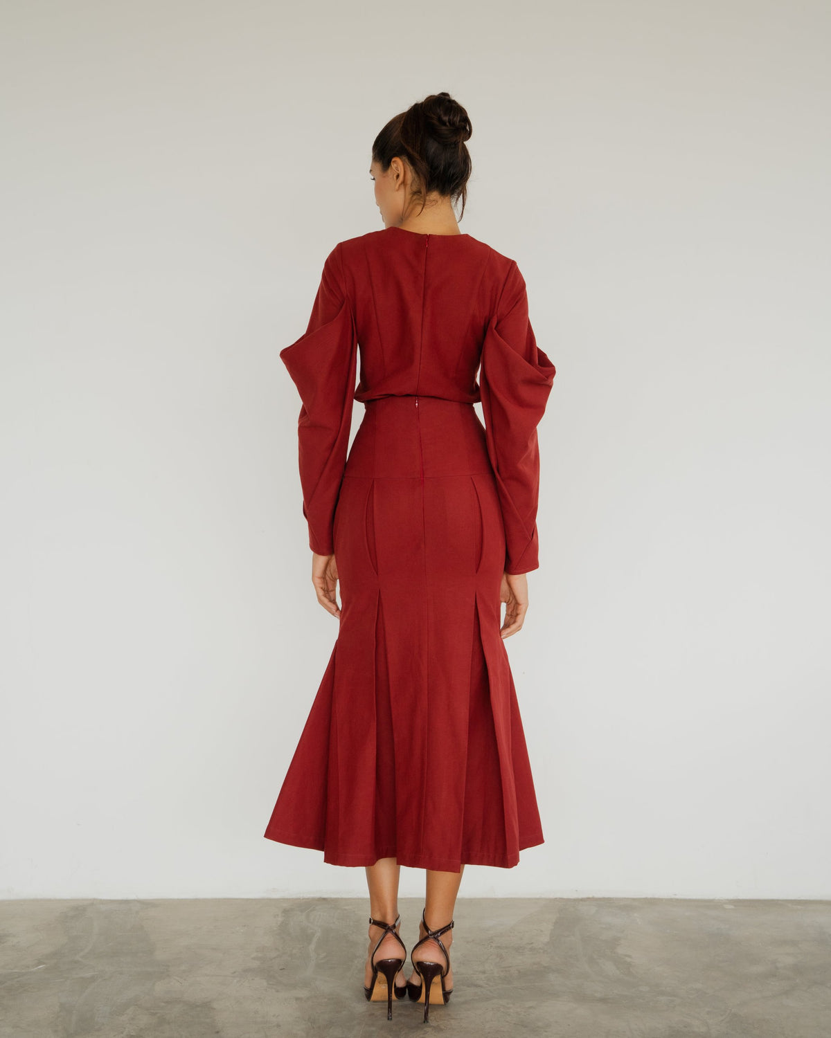 Model wearing the Anita Blouse in burgundy with the Neya Skirt, back view