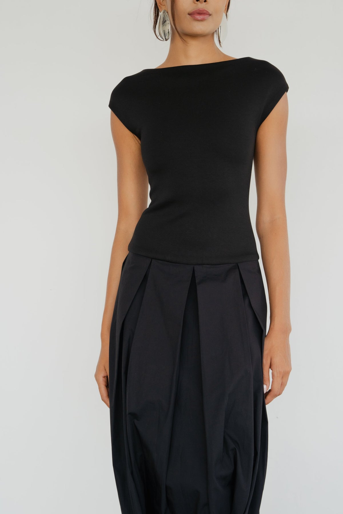 Model wearing the Lyon Dress in black, close-up of the bodice and pleated skirt