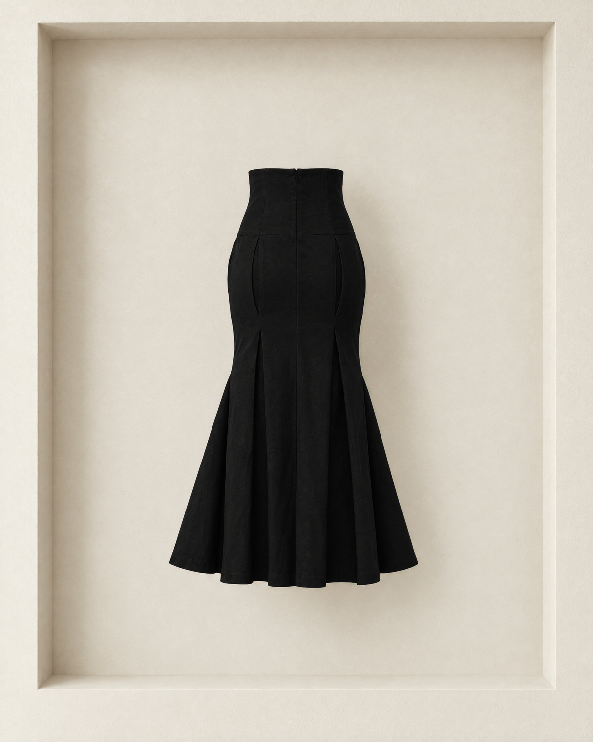 Neya Skirt in black, back view — centre-back zip, curved pleats and trumpet flare