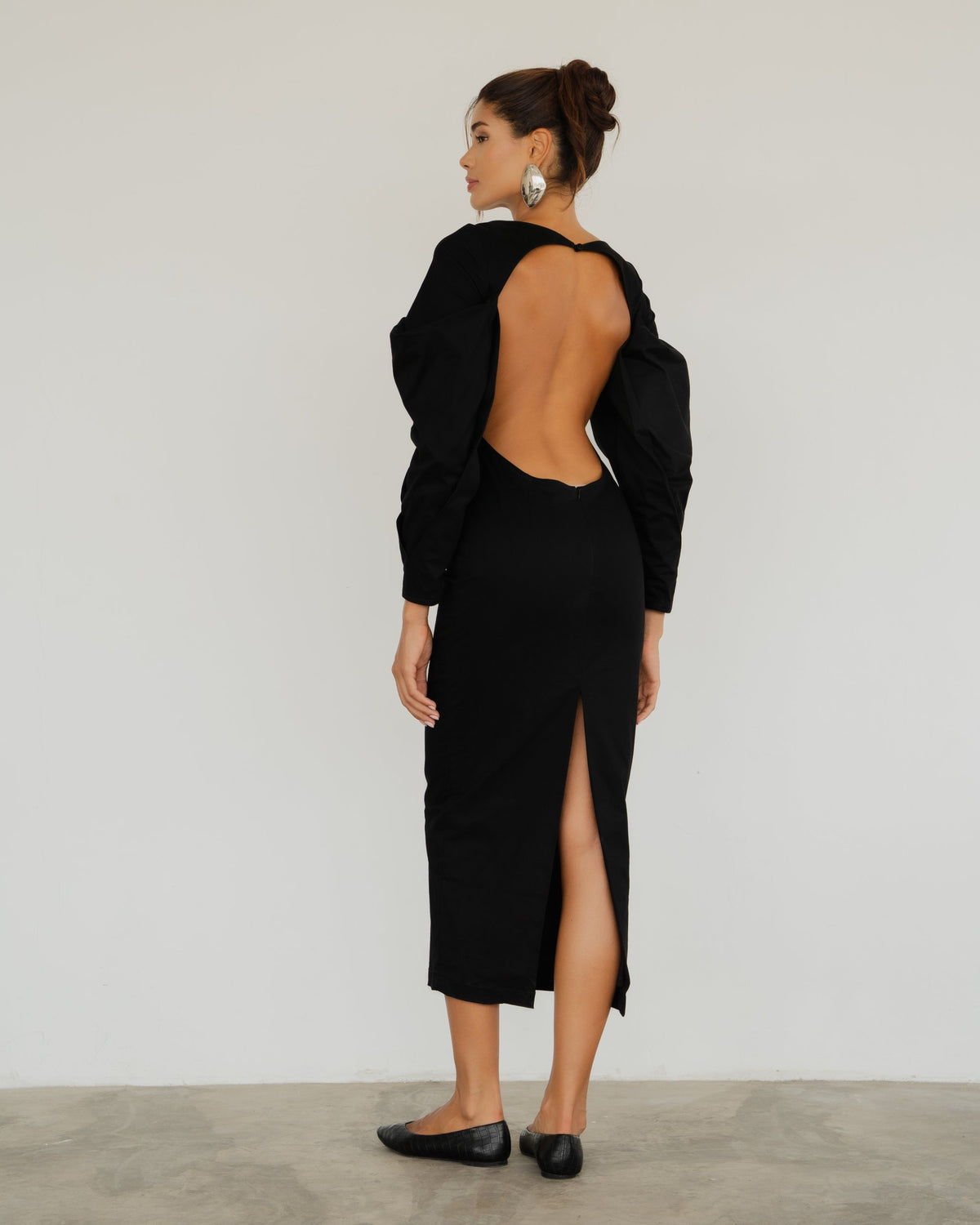 Model wearing the Seraphine Dress in black, back view showing the open back and slit
