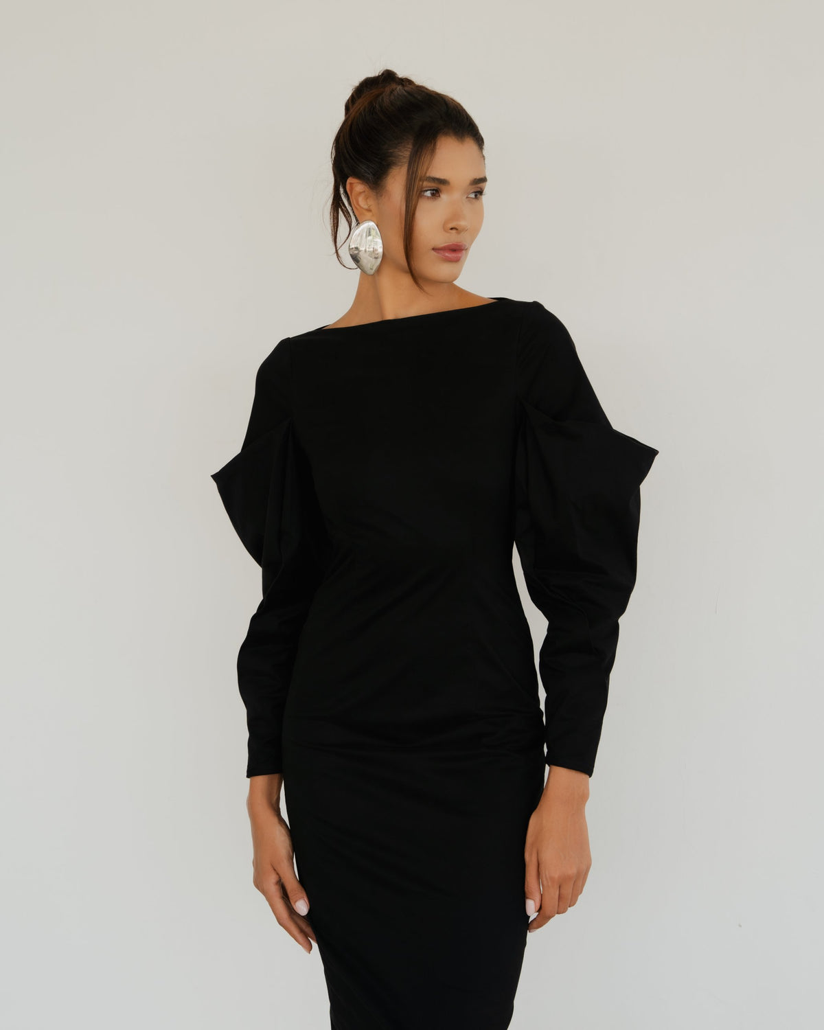 Model wearing the Seraphine Dress in black, close-up of the boat neckline and sculpted sleeves